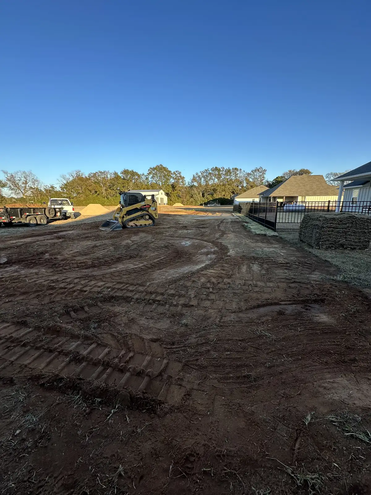 Sod pallets staged beside a graded residential installation site